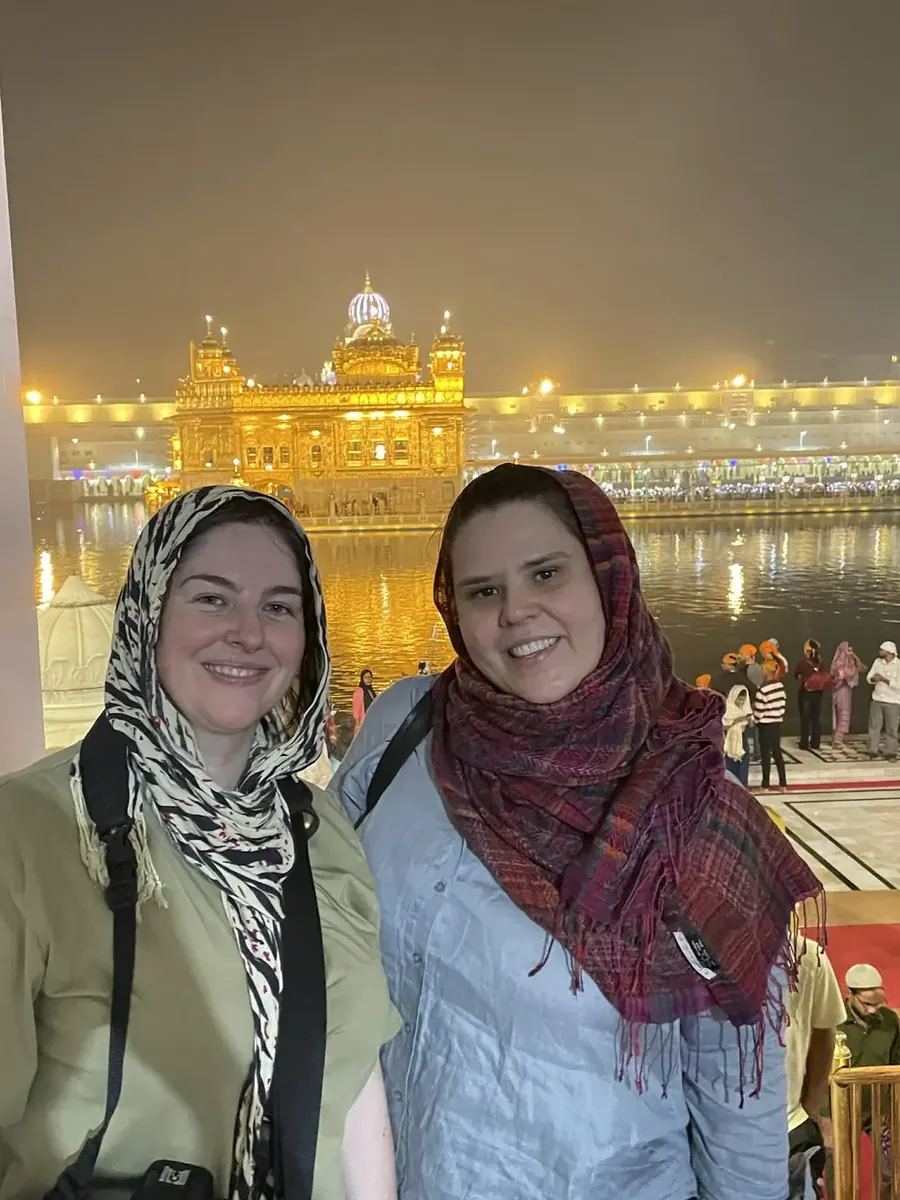 Visitors in headscarves before the illuminated Golden Temple at night, Amritsar heritage tour