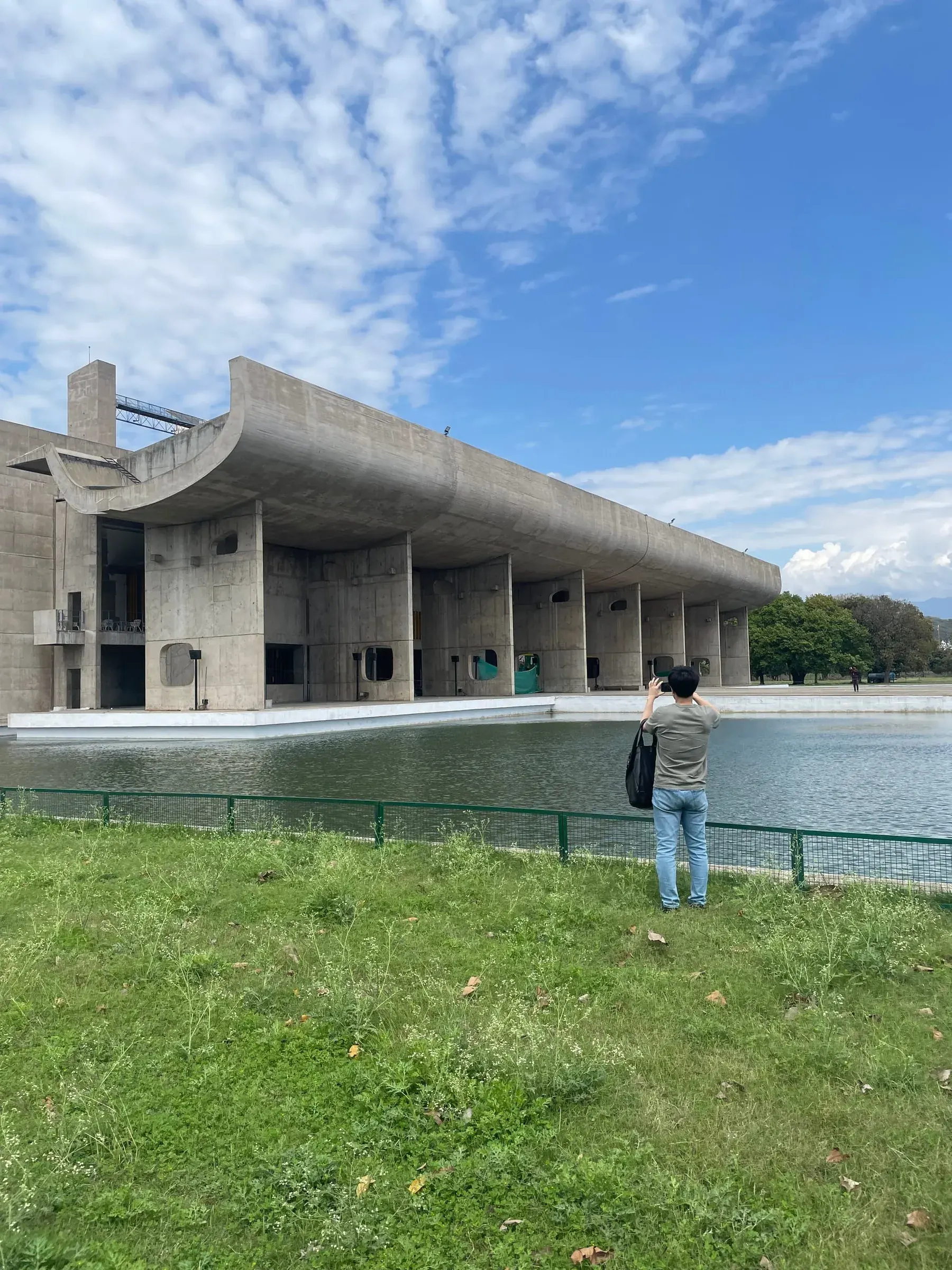 Visitor photographing the Palace of Assembly reflected in its pool, Le Corbusier Capitol Complex Chandigarh architecture tour