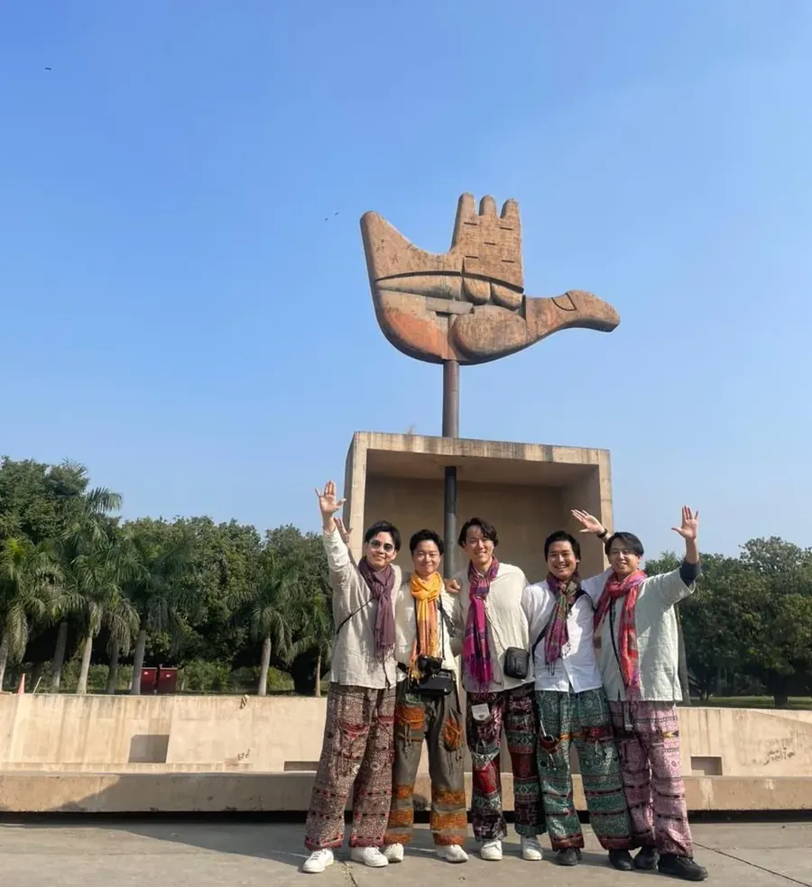 Tour group posing under Le Corbusier Open Hand Monument, Chandigarh architecture and design tour