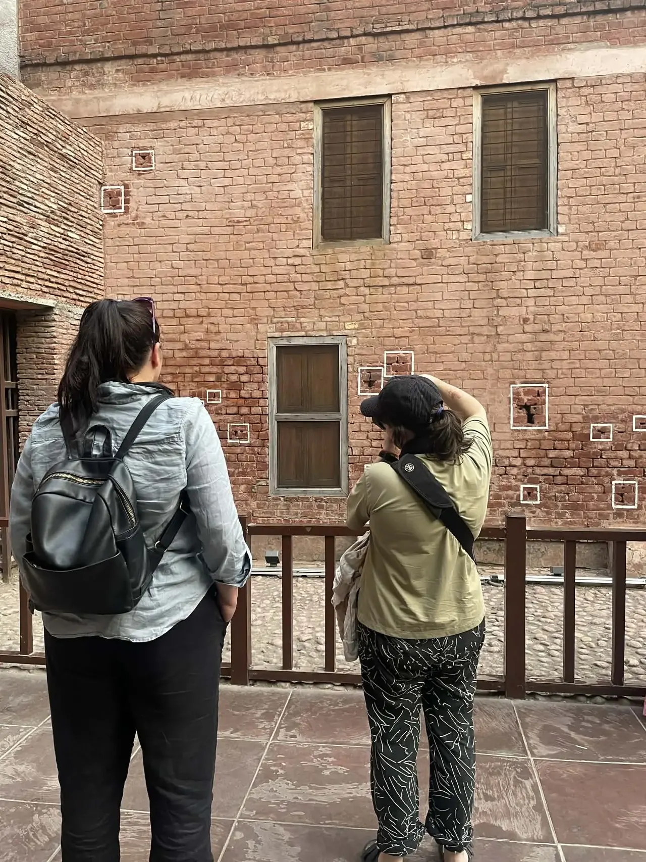 Visitors examining the marked bullet-hole scarred wall at Jallianwala Bagh Massacre Memorial, Amritsar heritage tour