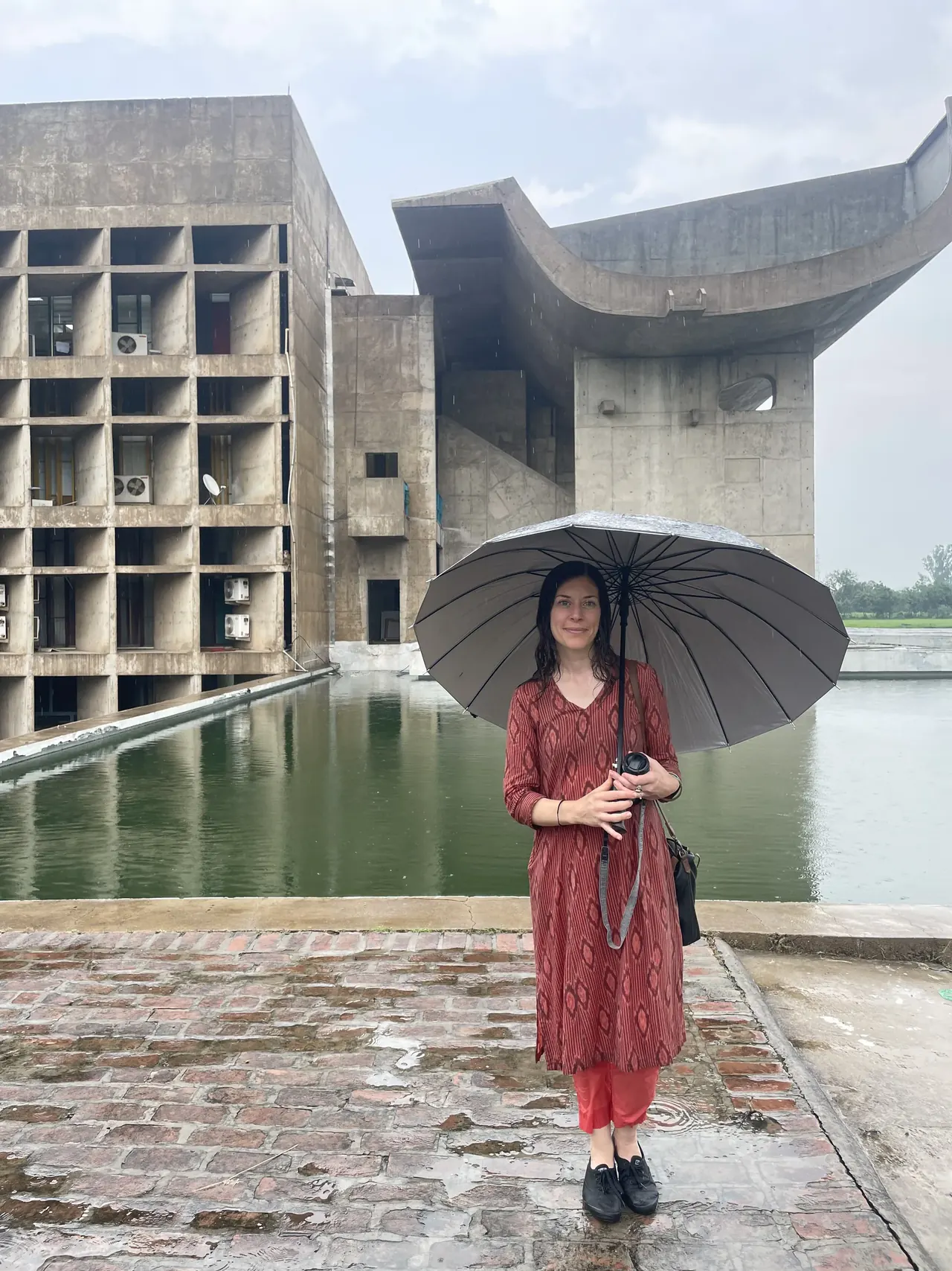 Visitor with umbrella at the Palace of Assembly on a rainy day, Chandigarh Le Corbusier architecture tour